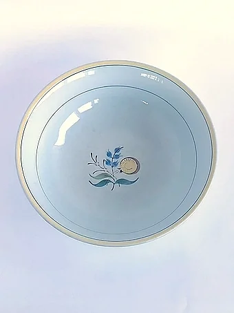 White bowl with yellow rim and blue ring, featuring a hand-painted blue and yellow floral motif in the center