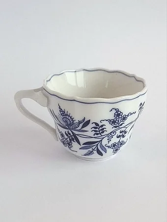 White porcelain cup with scalloped rim and blue Zwiebelmuster onion pattern decoration