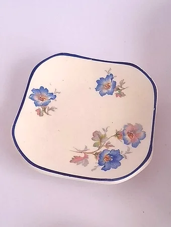 Cream earthenware platter with rounded square shape, cobalt blue rim, decorated with scattered blue flowers with pink and orange centers