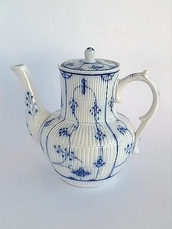 White porcelain teapot with vertical ribbed texture and delicate blue floral sprigs
